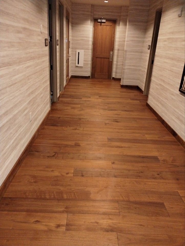 Empty hallway with wood flooring, beige walls, and a closed wooden door at the end.