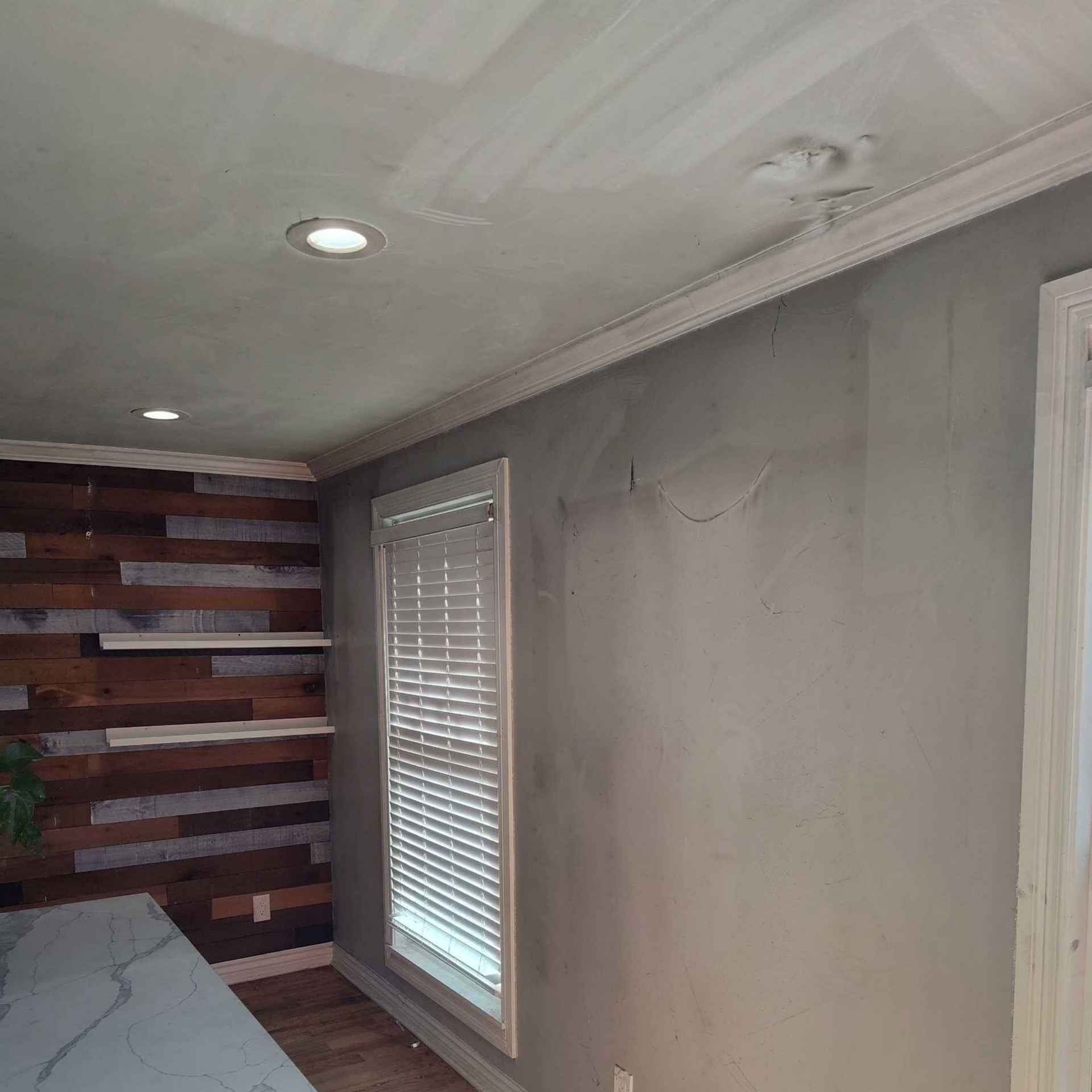 Narrow room with gray walls, white ceiling lights, a window, and a wood accent wall.