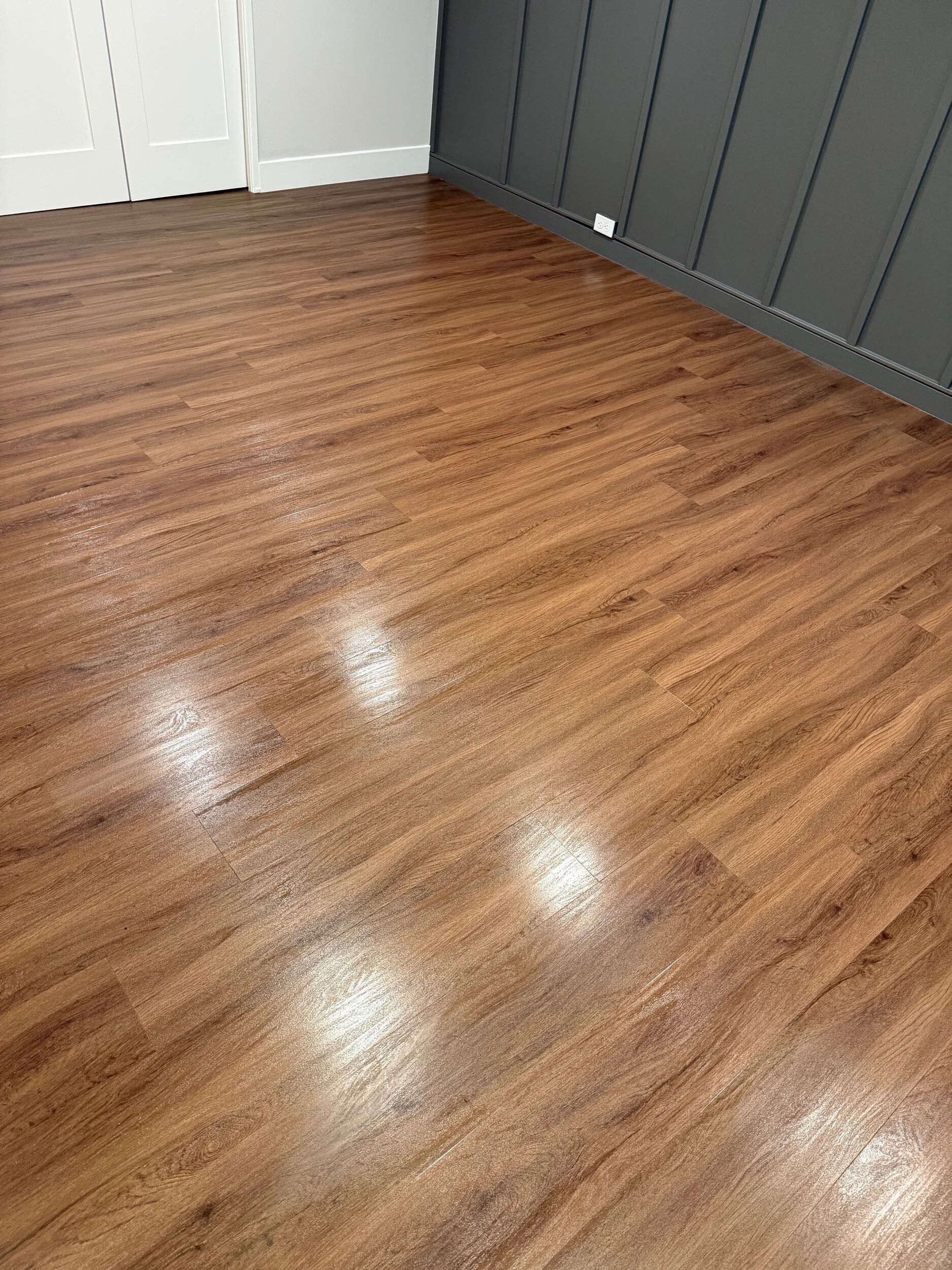 Empty room with glossy wood flooring and gray paneled walls.