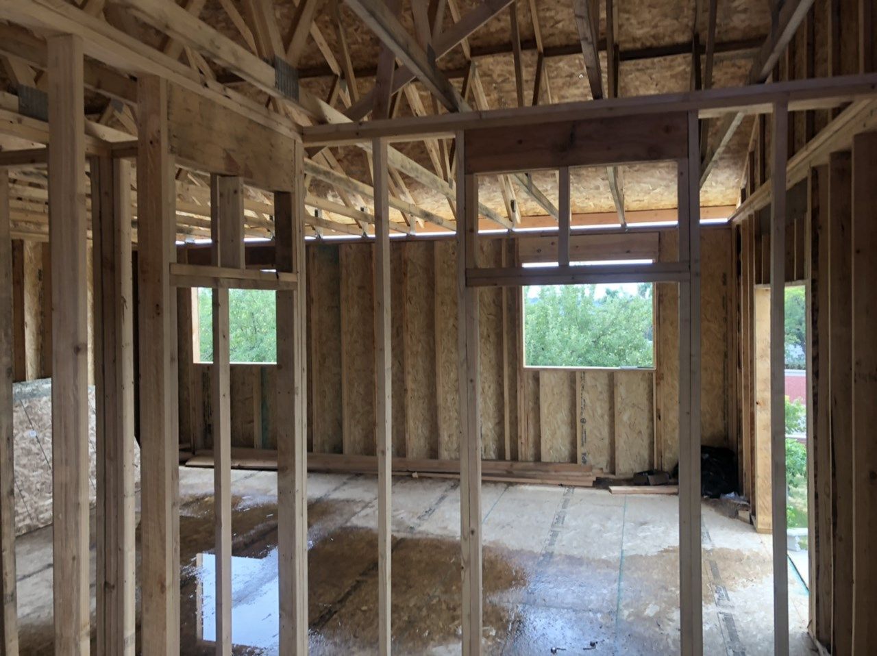 Interior of a framed house under construction with exposed wooden beams and unfinished walls