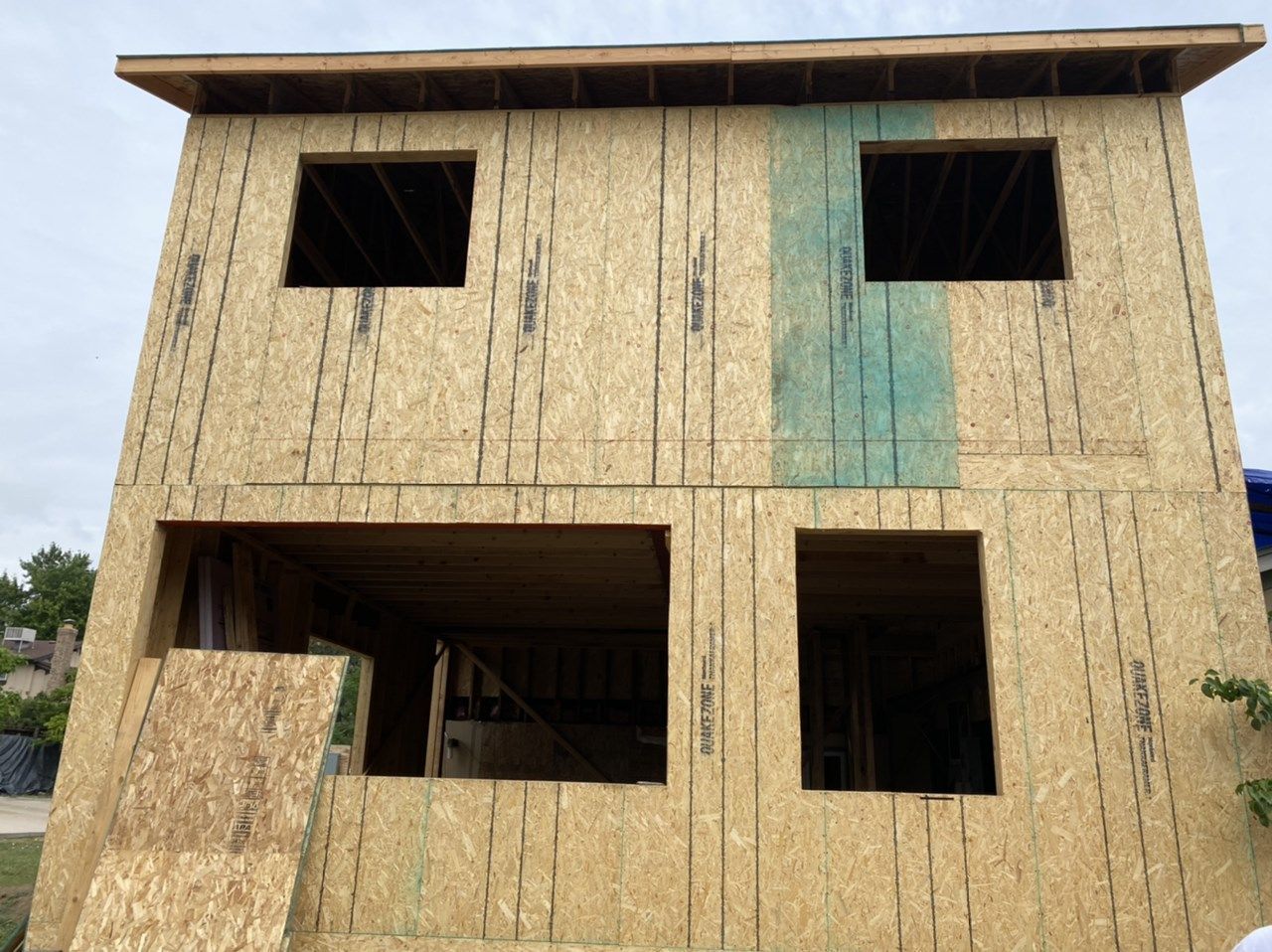 Partially built two-story wooden house with open window and door cutouts