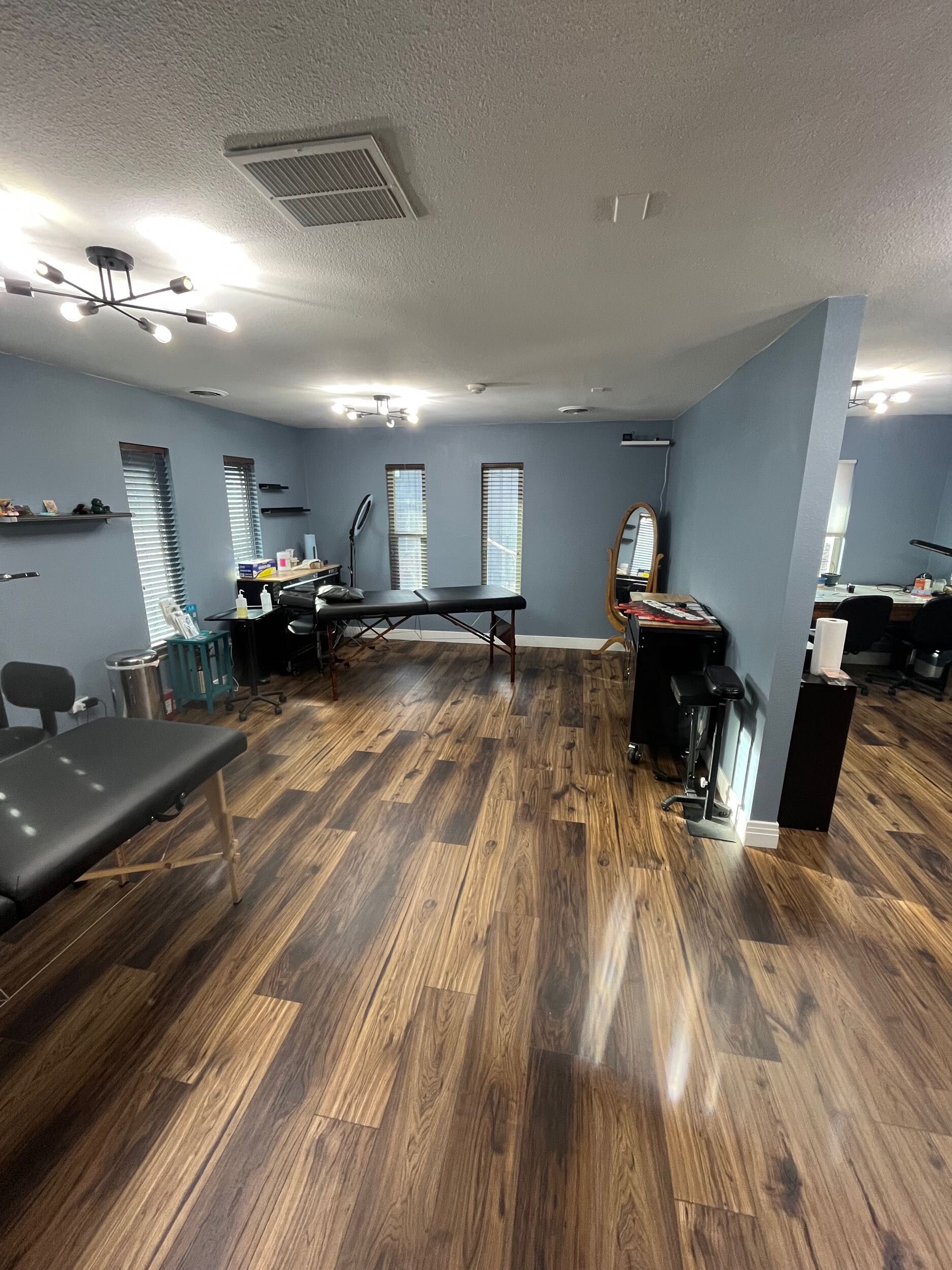 Wide dance studio with blue walls, wood floor, mirrors, and exercise equipment along the sides.