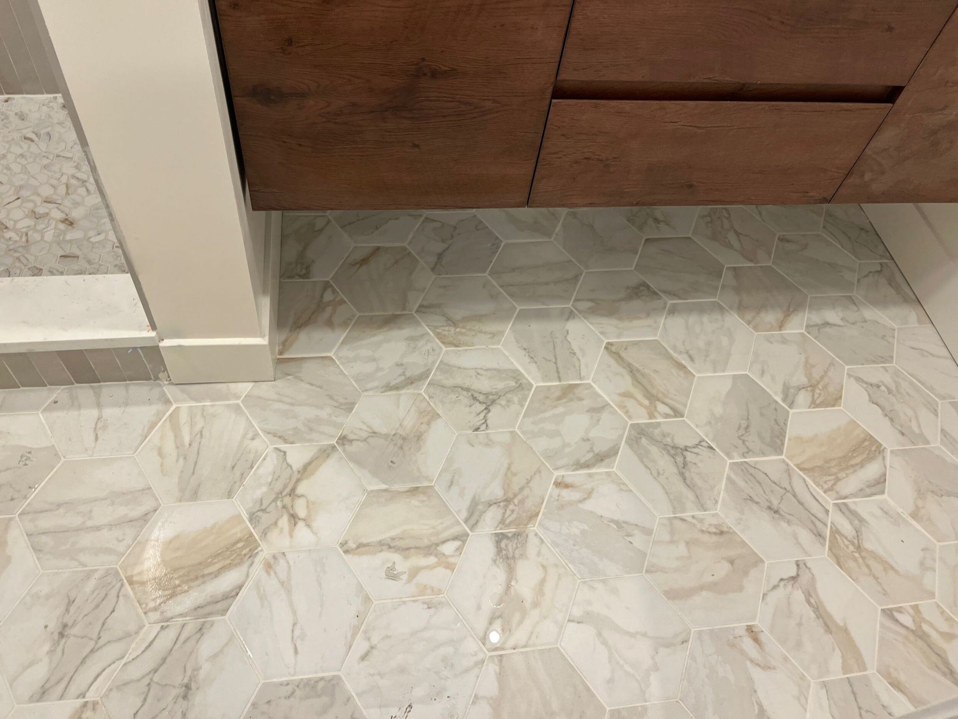Marble-pattern tile floor beside a wooden cabinet and wall corner