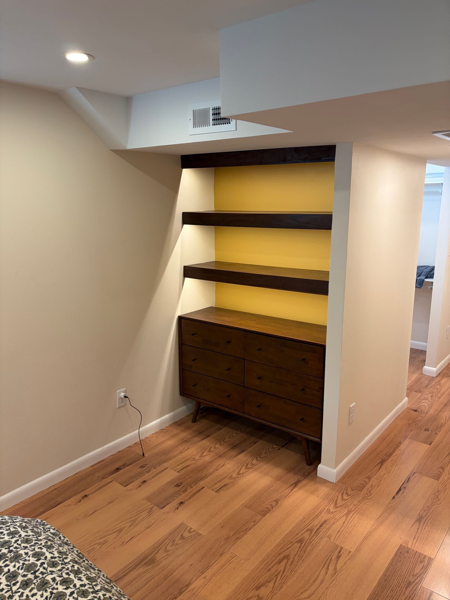 Built-in nook with dark wood shelves and cabinet in a beige room with hardwood floor.
