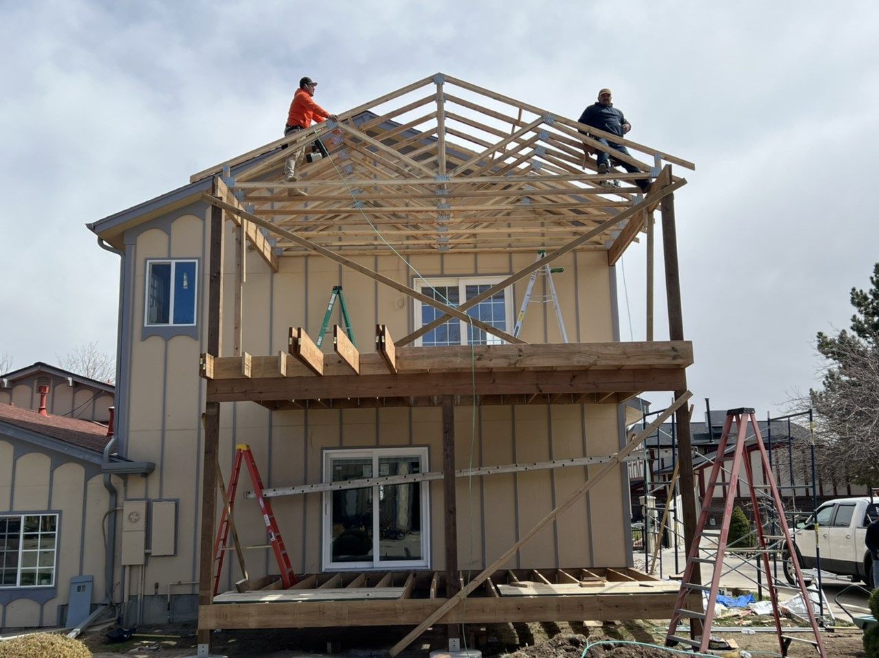 House under construction with workers on the roof framing a new second-story addition