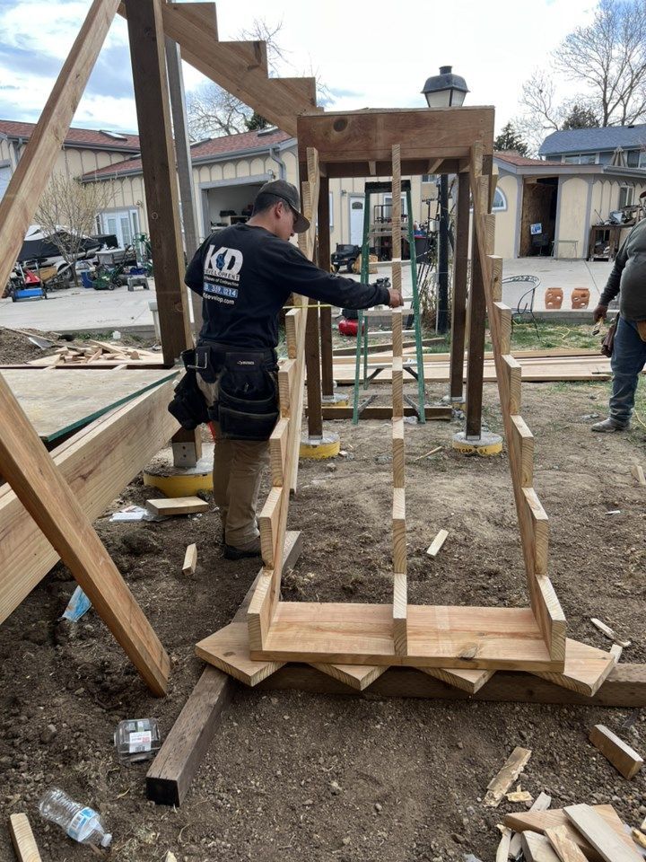 Workers building a wooden outdoor structure at a construction site, with framing and steps in progress