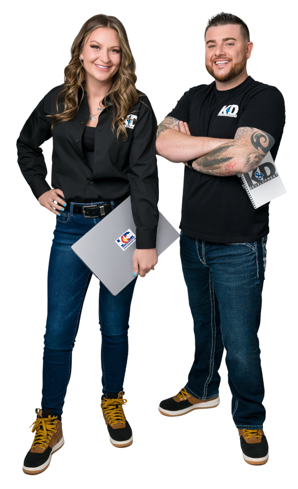 Two smiling staff members in black shirts and jeans holding gray clipboards, standing against a white background