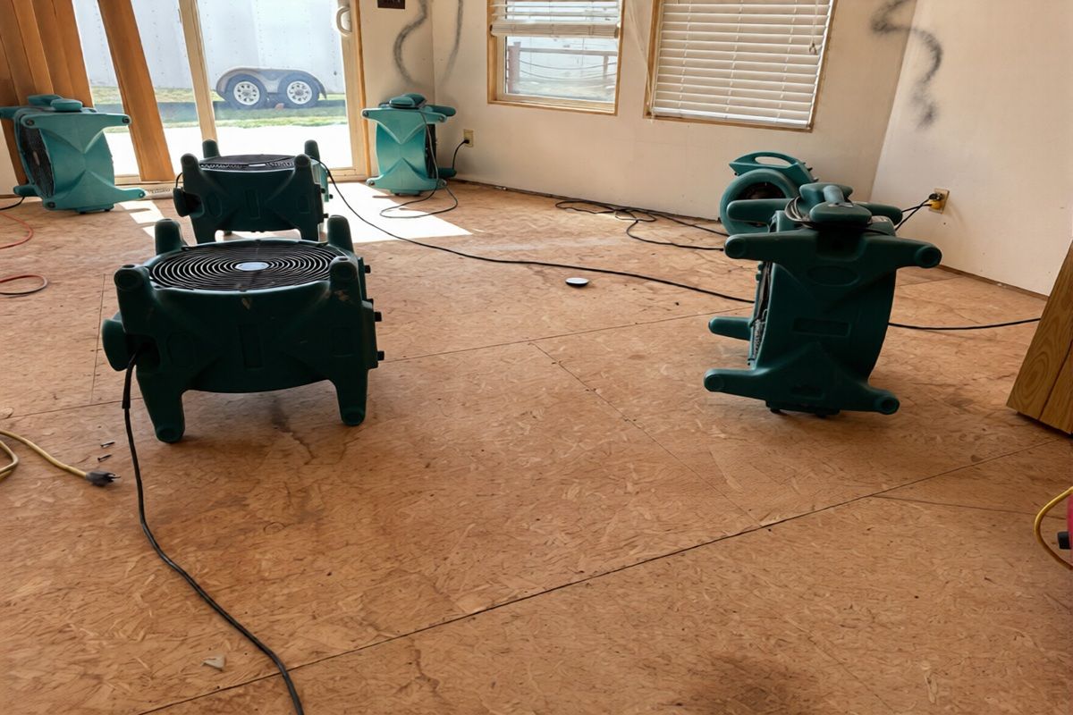 Empty living room with scattered power tools and debris on a plywood floor