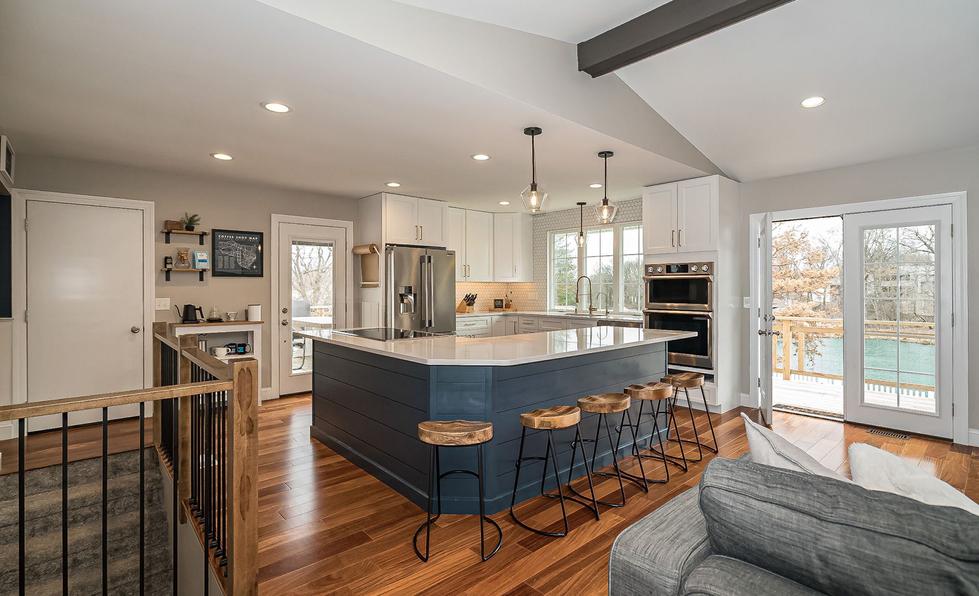 Bright modern kitchen and living area with navy island, barstools, hardwood floors, and French doors to outside