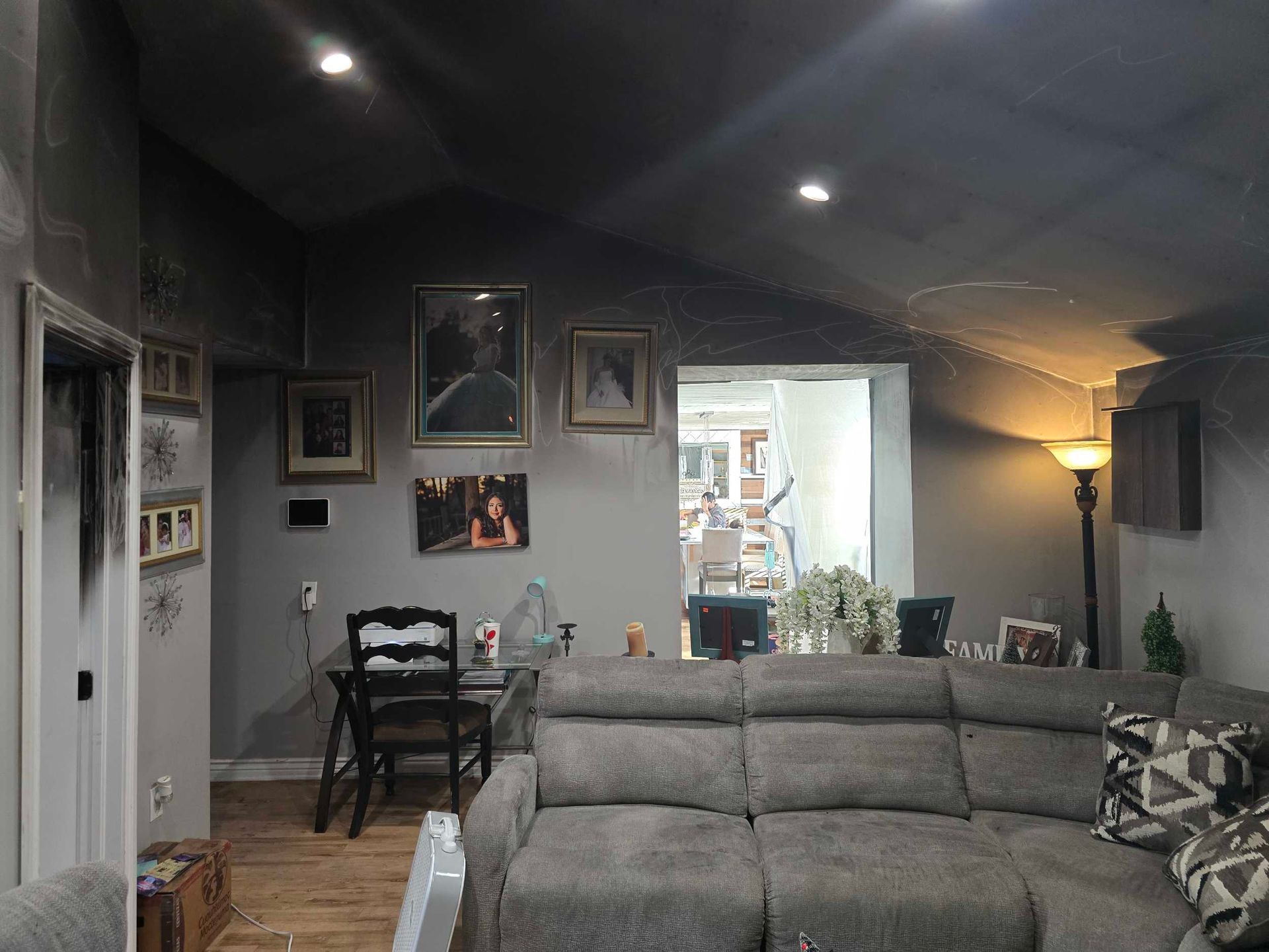 Cozy living room with gray sectional sofa, wall art, desk, and floor lamp under a vaulted ceiling