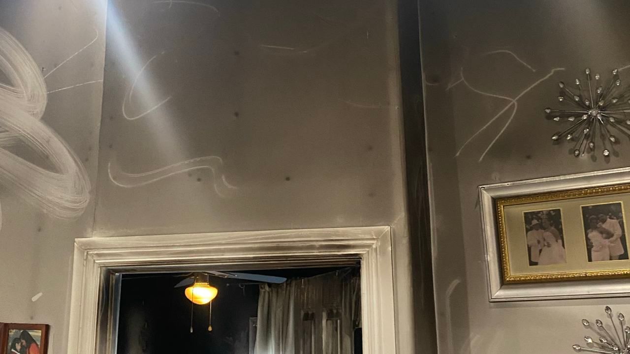Dim room interior with gray walls, a doorway, wall art, and decorative starburst mirrors.