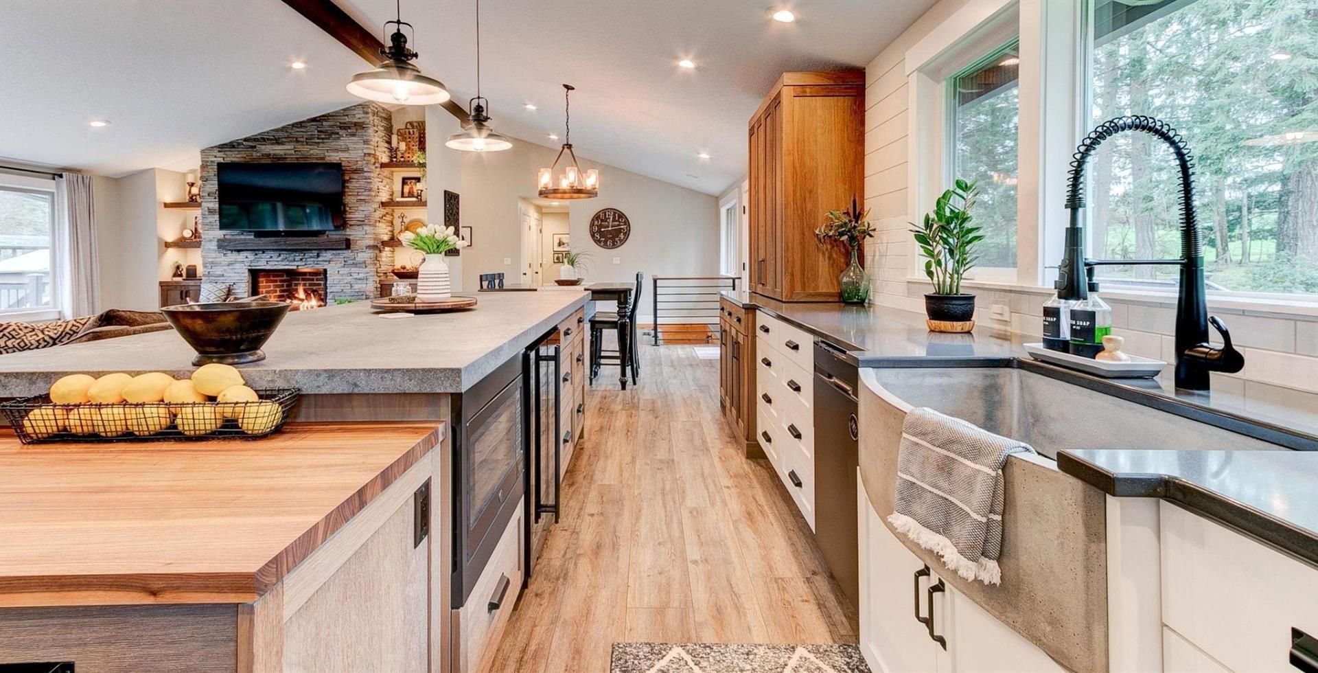Bright modern kitchen with white cabinets, large island, and black countertop sink by a window