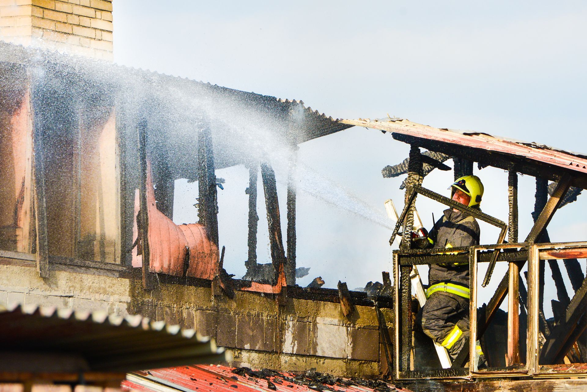 Firefighters spraying water on a burning building from a metal platform as smoke rises.