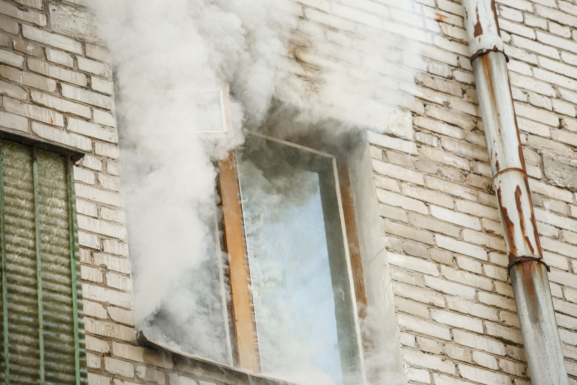 Smoke billowing from a window in a brick building exterior