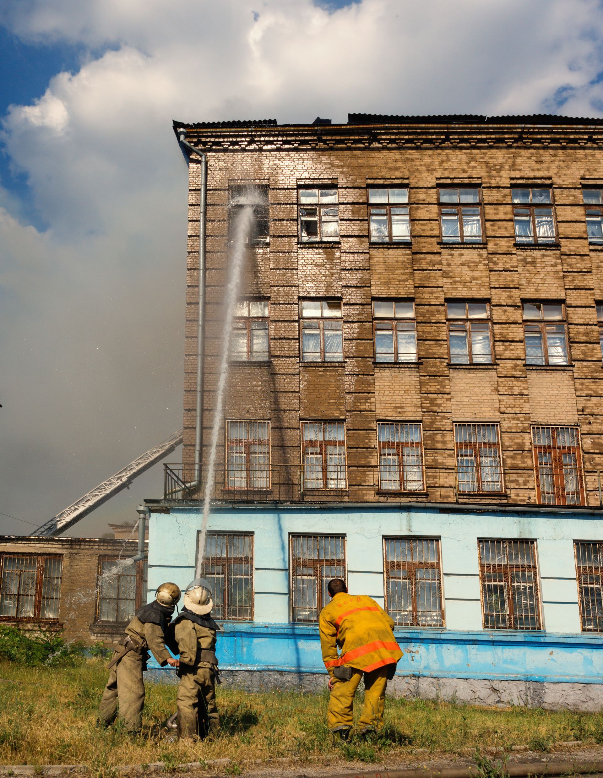 Firefighters spraying water at a brick building during a fire response