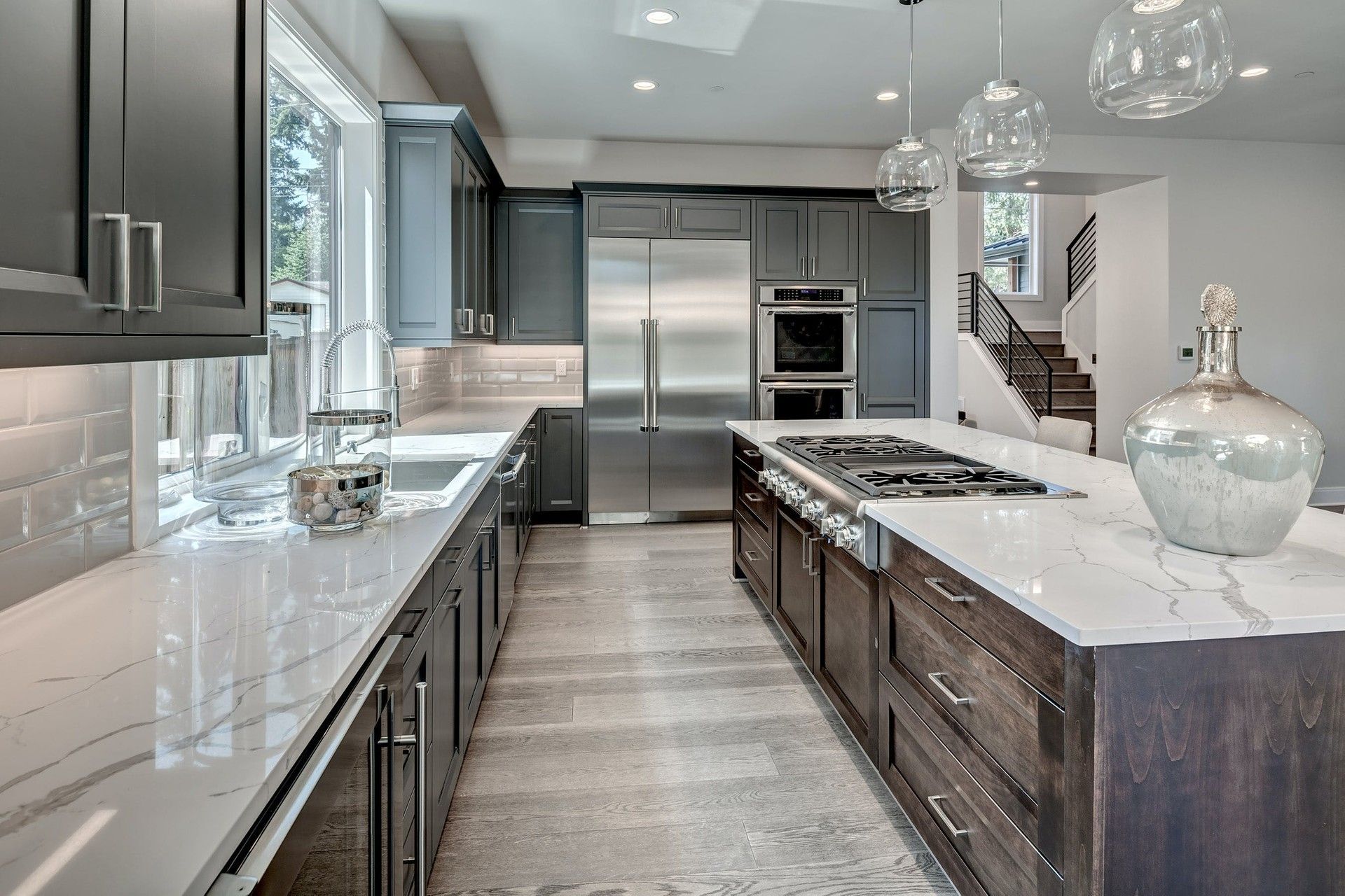 Modern gray kitchen with marble island, stainless steel appliances, and pendant lights