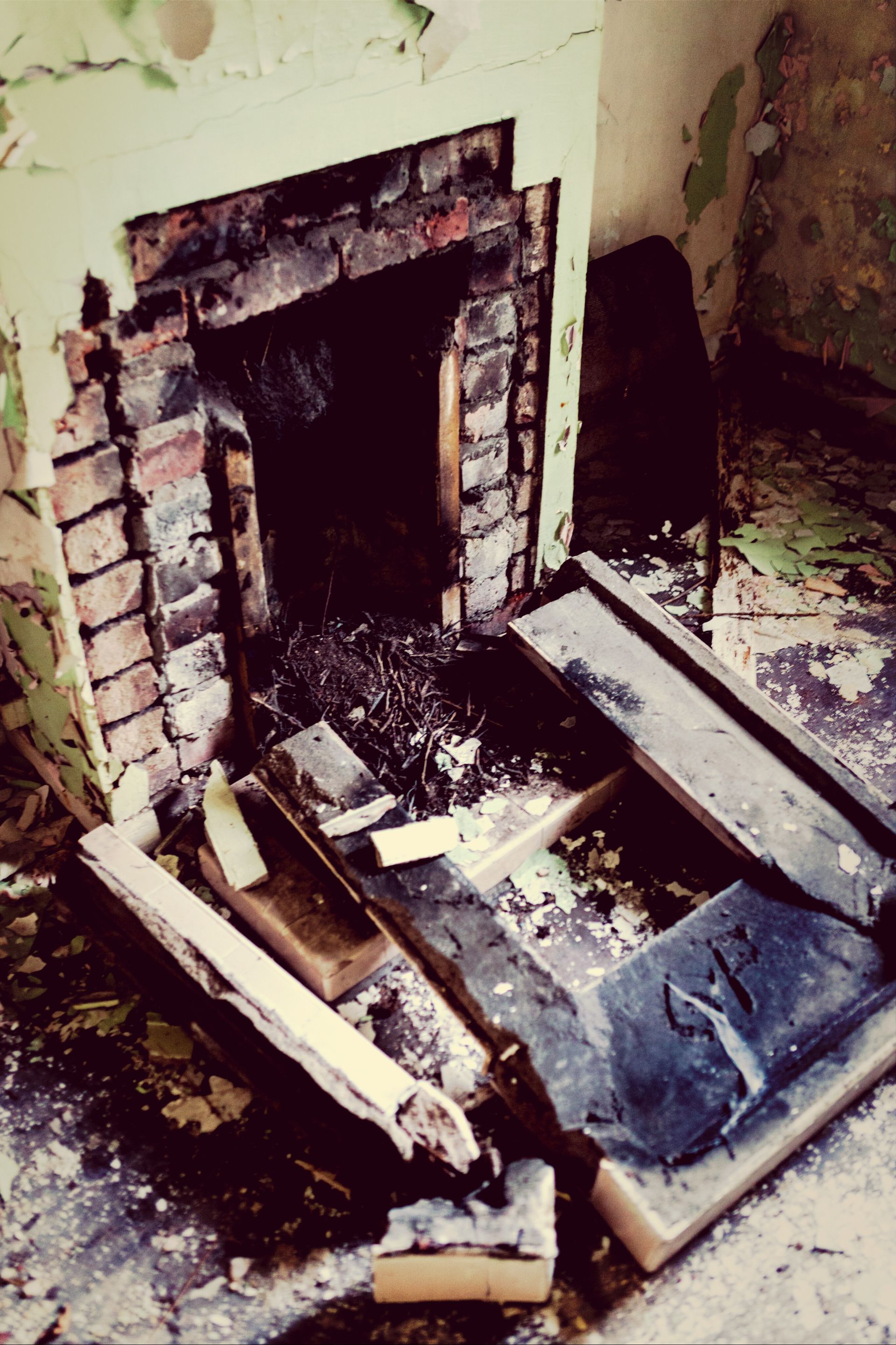 Burned fireplace with charred debris and broken boards in a ruined room