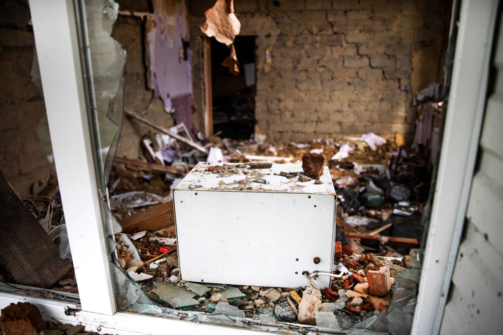 Destroyed storefront interior with debris and a broken white counter amid damaged walls and shattered glass