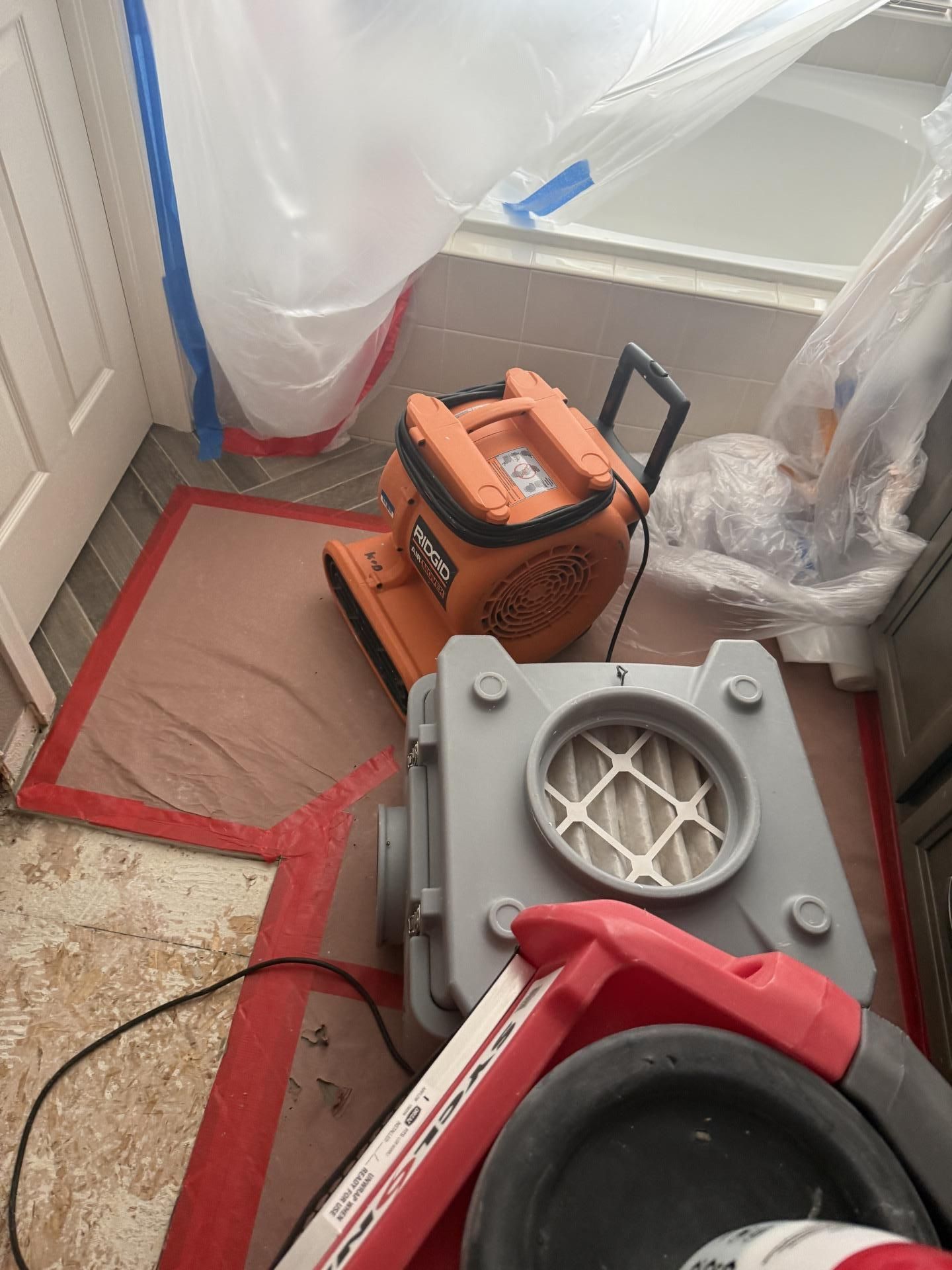 Fans and air scrubber in a room under plastic dust containment during renovation