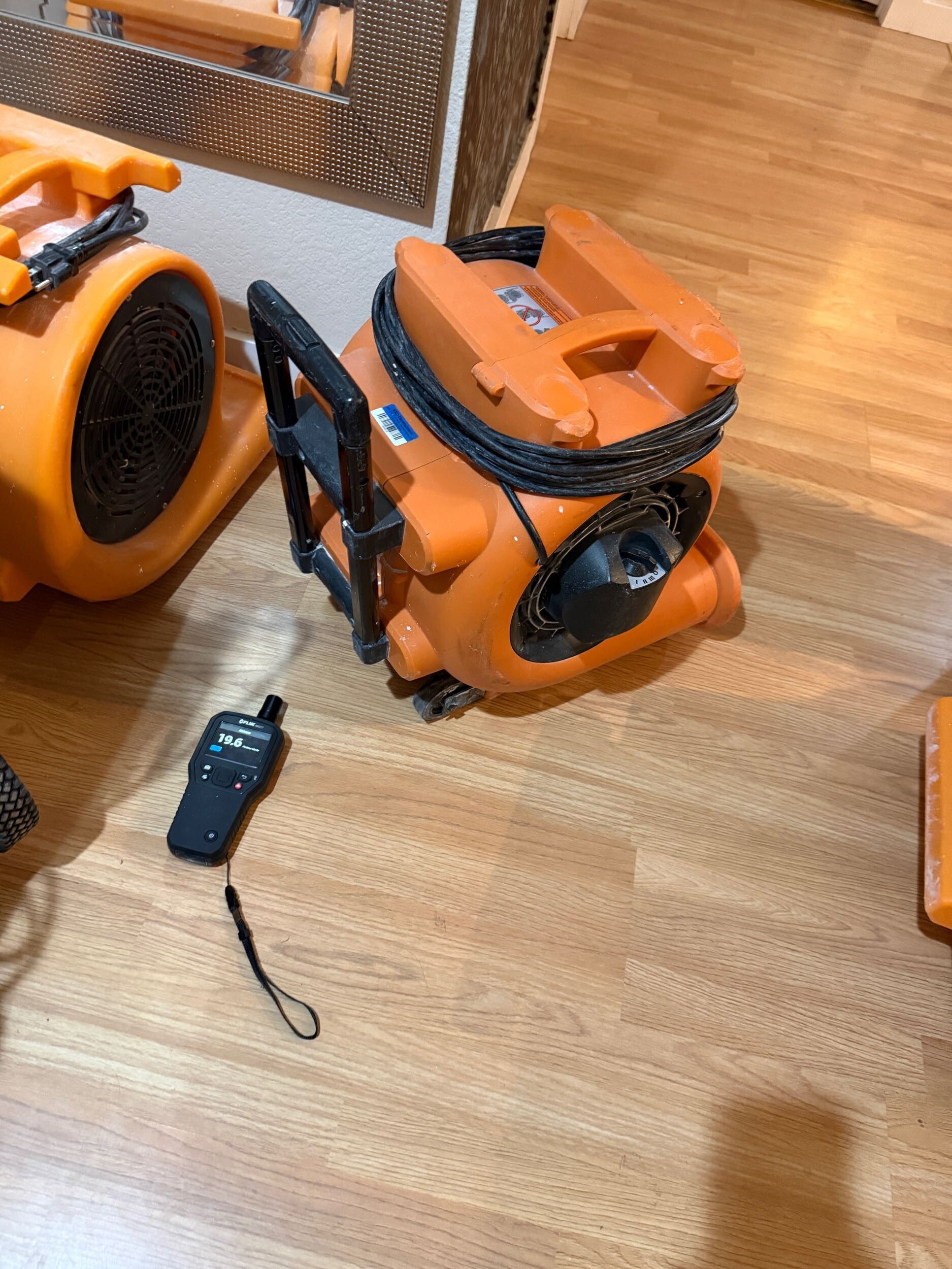 Orange leaf blowers and a handheld controller on a wooden floor.