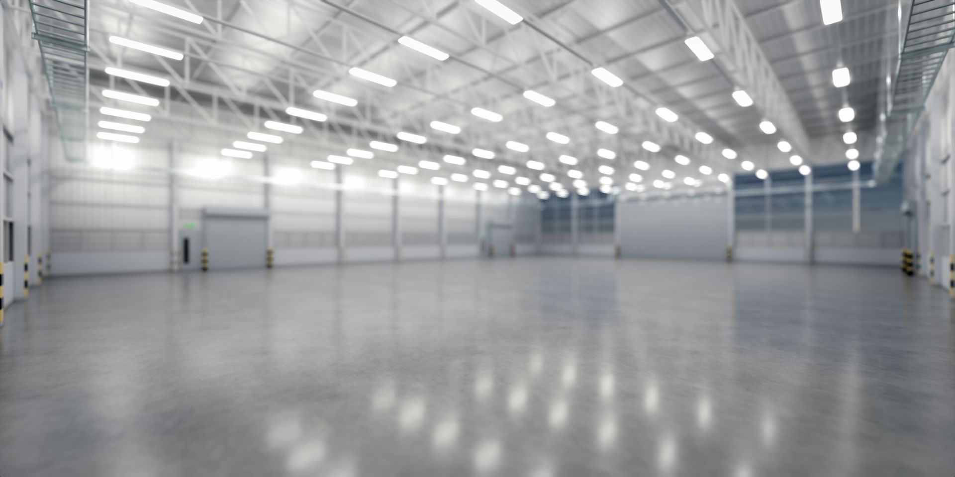 Empty bright industrial warehouse interior with high ceilings, skylights, and polished concrete floor