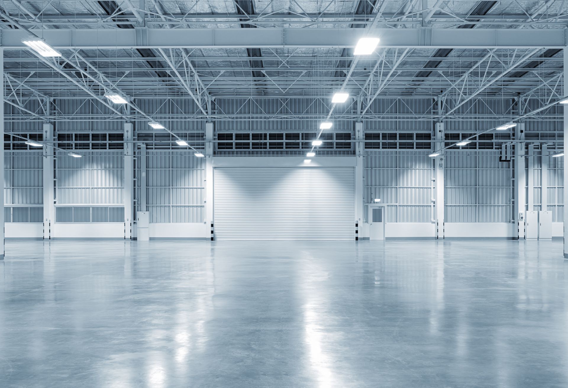 Empty industrial warehouse with high ceilings, metal beams, and polished concrete floor