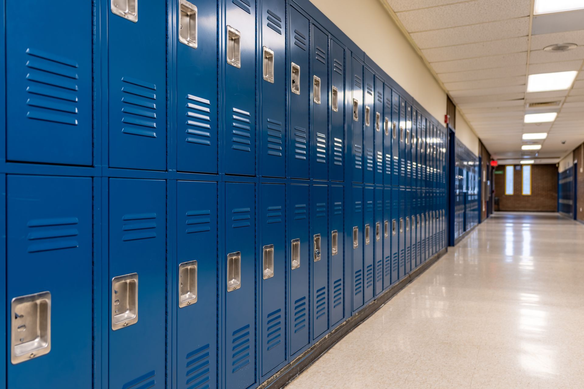 Long row of blue school lockers in a bright hallway with a polished floor