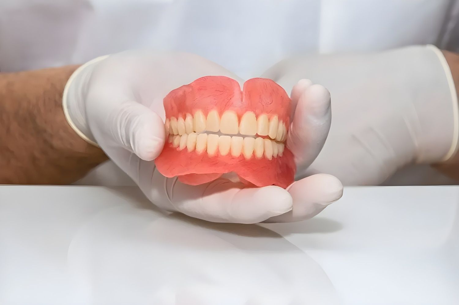 A Dentist is Holding a Denture in His Hands — Jaw Gear Dental Prosthetics in Bowral, NSW