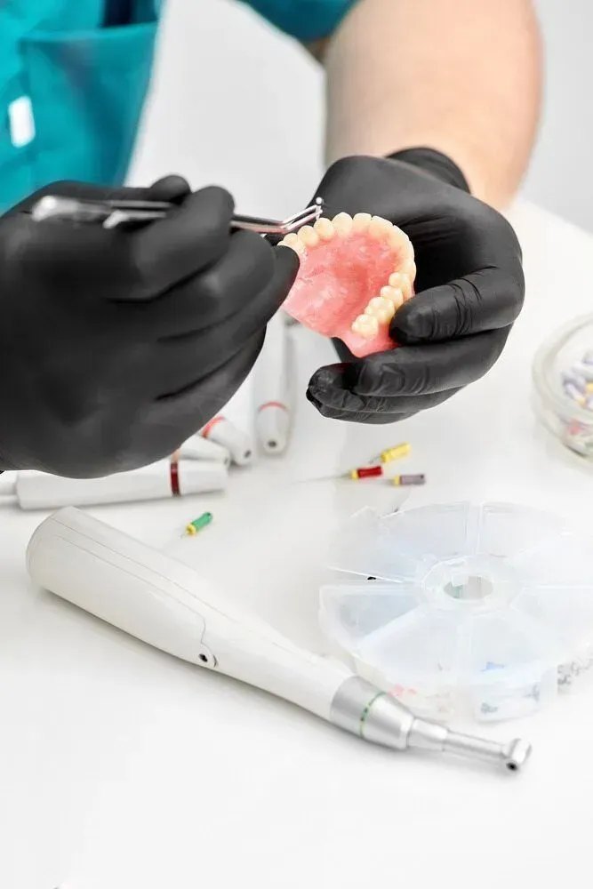 A Dentist is Working on a Denture With a Pair of Scissors — Jaw Gear Dental Prosthetics in Moss Vale, NSW