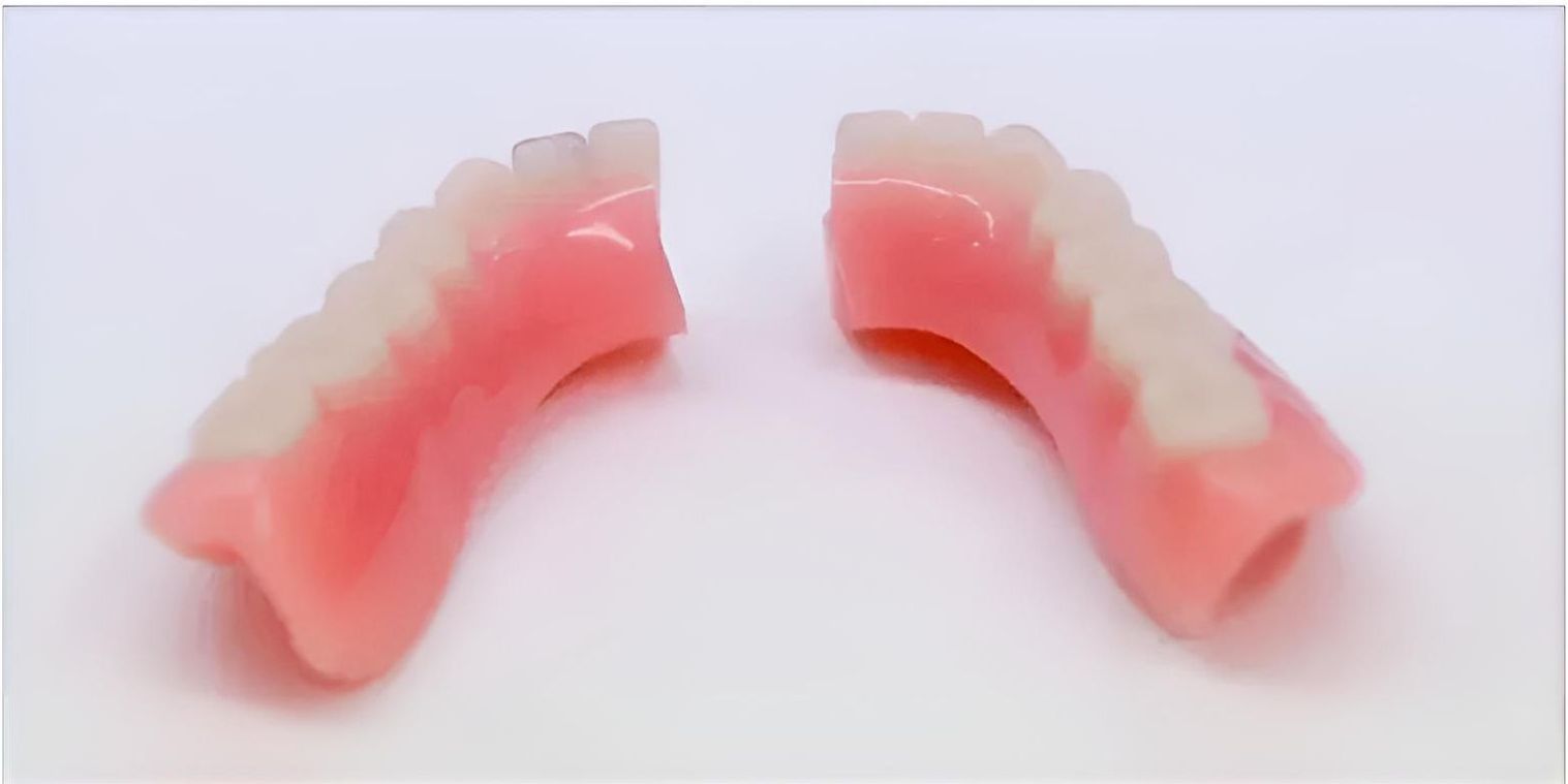 A Pair of Dentures Are Sitting on Top of Each Other on a White Surface — Jaw Gear Dental Prosthetics in Bowral, NSW