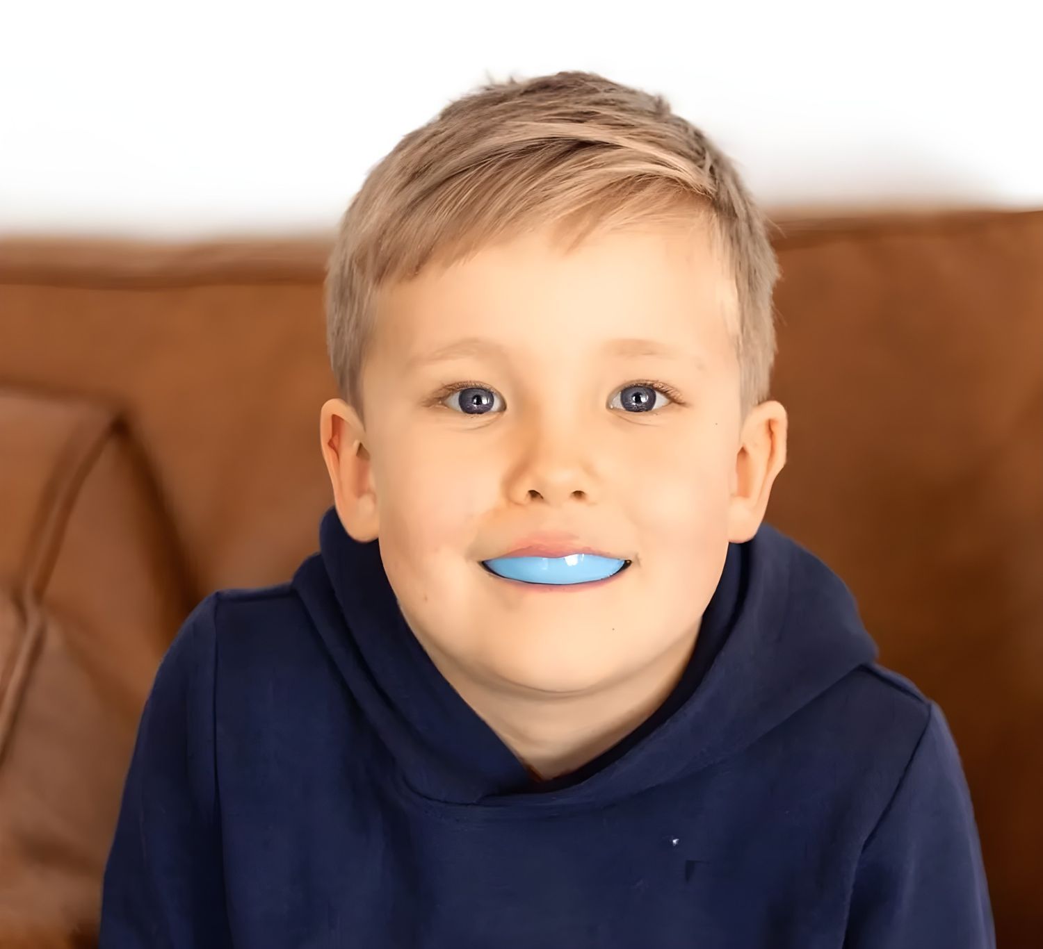 A Young Boy With Blonde Hair and a Blue Mouthguard Smiles — Jaw Gear Dental Prosthetics in Bowral, NSW