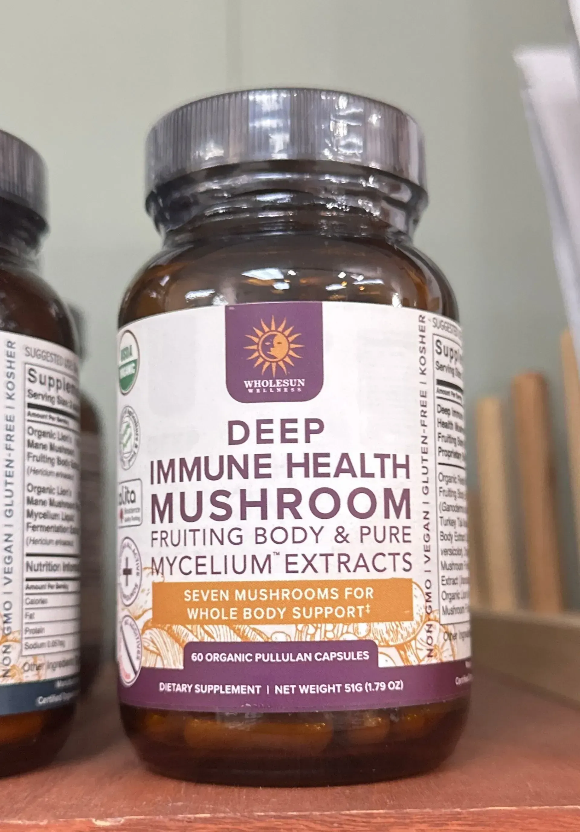 Bottle of Deep Immune Health Mushroom supplement on a store shelf, brown glass jar with silver lid.