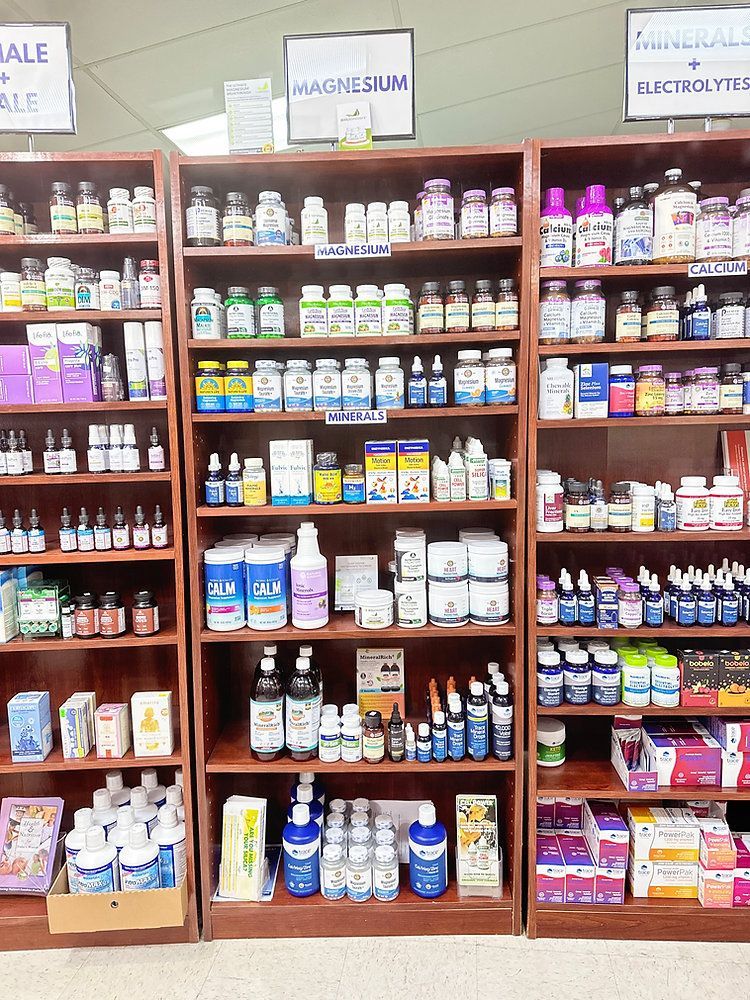 Shelves of health supplements and vitamins in a store aisle, with signs for calcium, magnesium, and electrolyte products