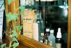 Vintage bottles and a pharmacy label behind glass, with green reflections and a wooden shelf.