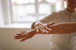 Person reaching out a hand during a yoga stretch in a bright room