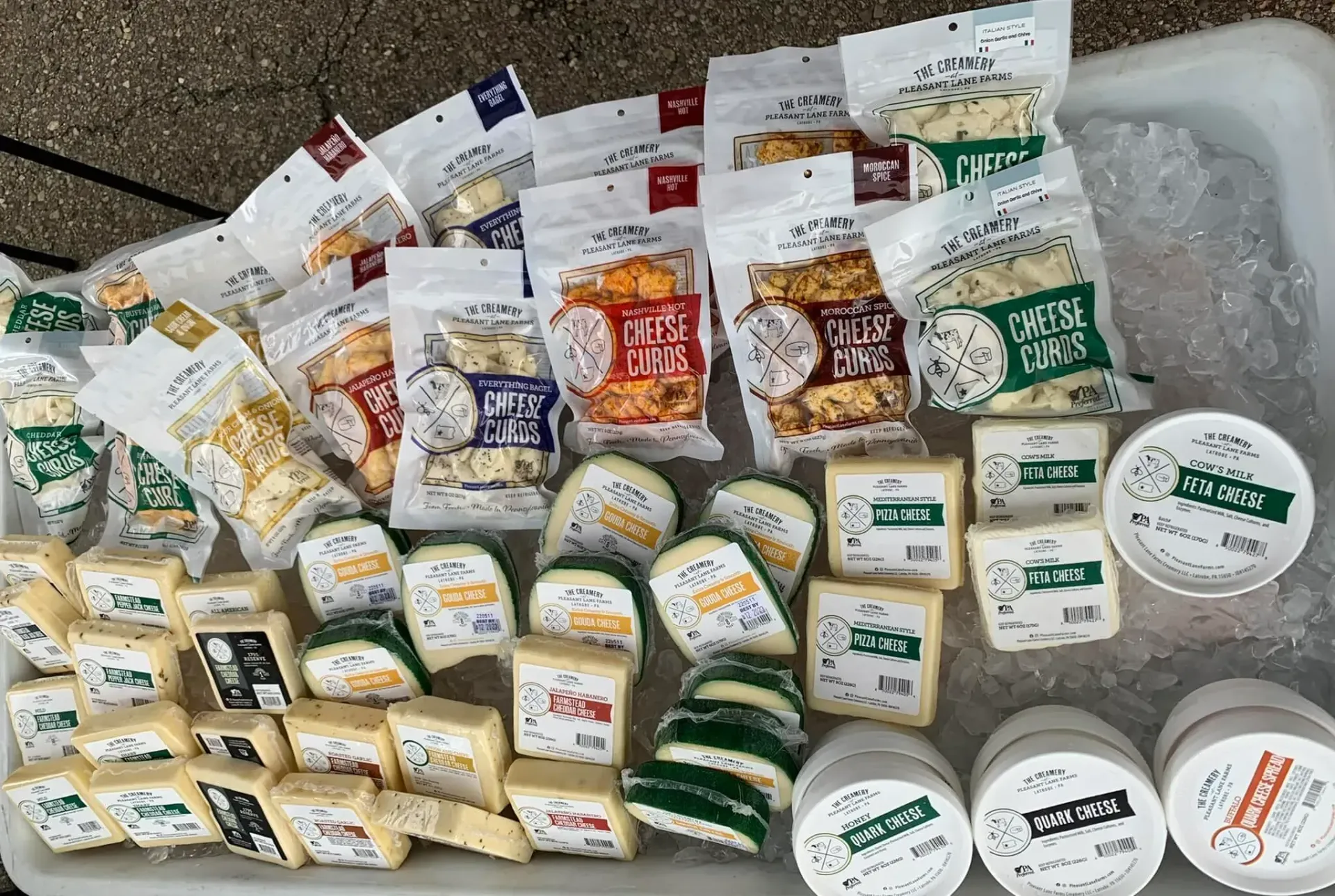 Assorted packaged cheeses and dairy products arranged on a floor with bubble wrap.