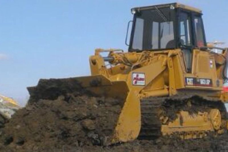 Yellow bulldozer pushing a large pile of dirt at a construction site