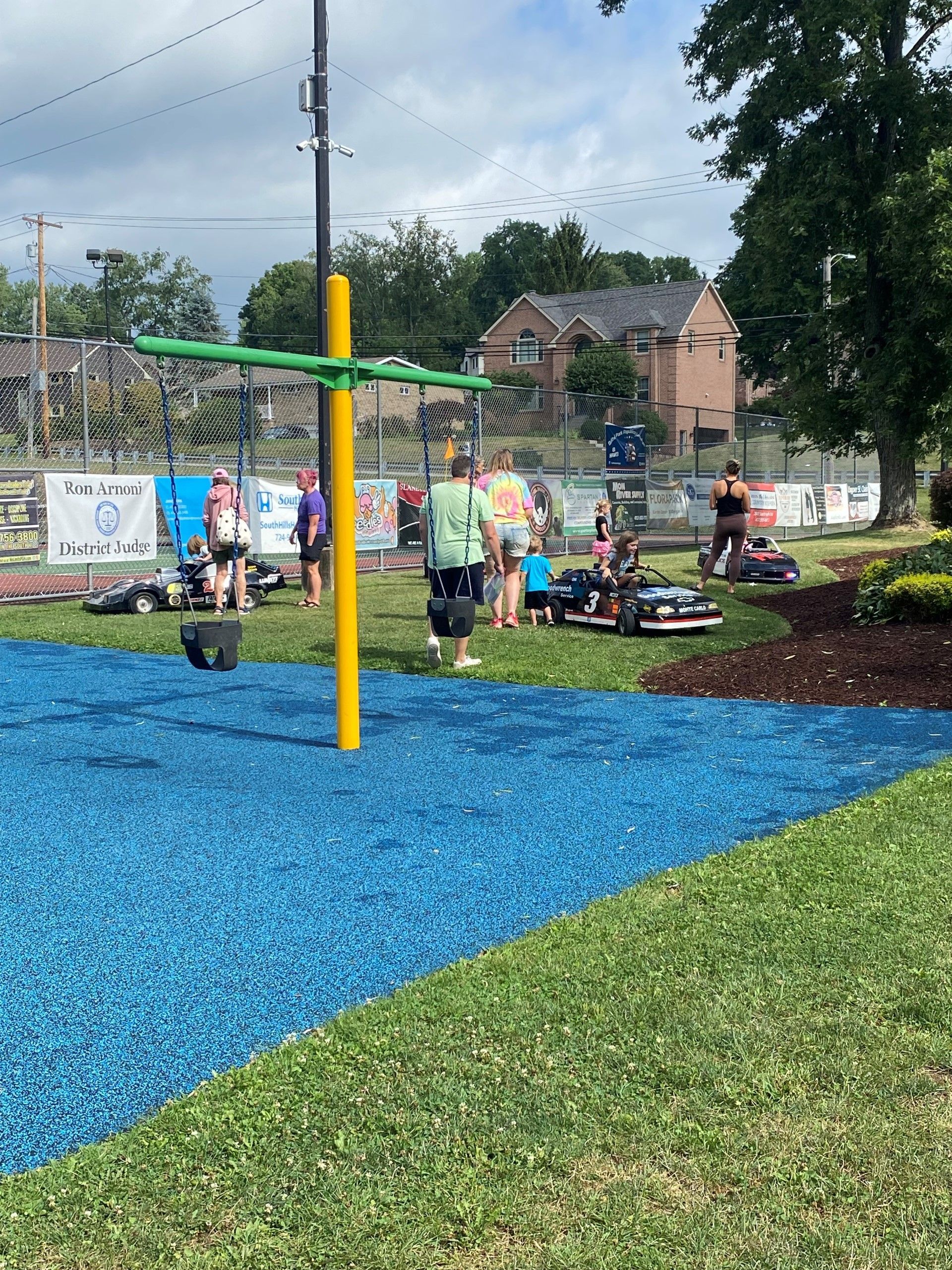 Colorful playground with blue rubber ground, play equipment, and children in a park setting