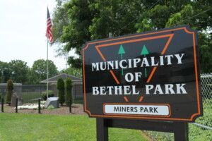 Sign reading “Municipality of Bethel Park” with “Miners Park” beneath, beside an American flag.