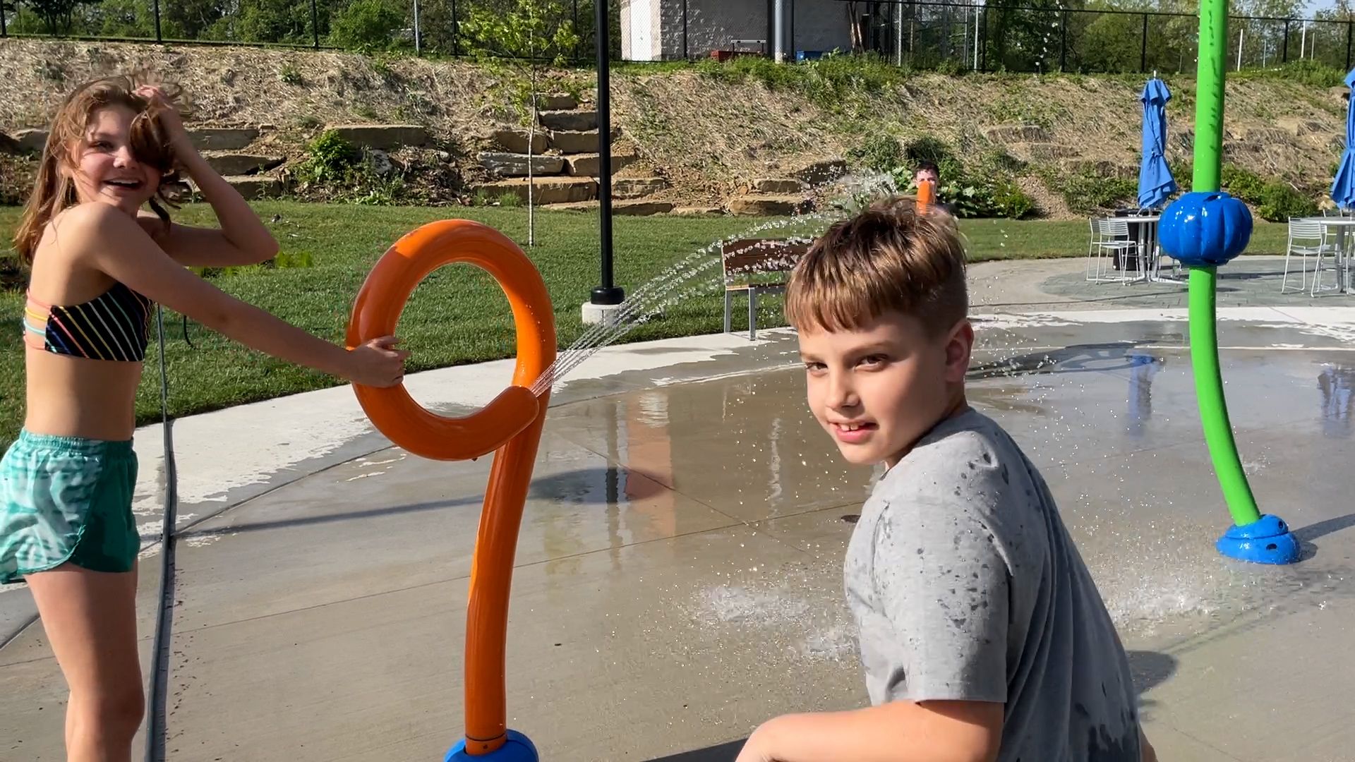 Children playing at a colorful splash pad with water spraying around them