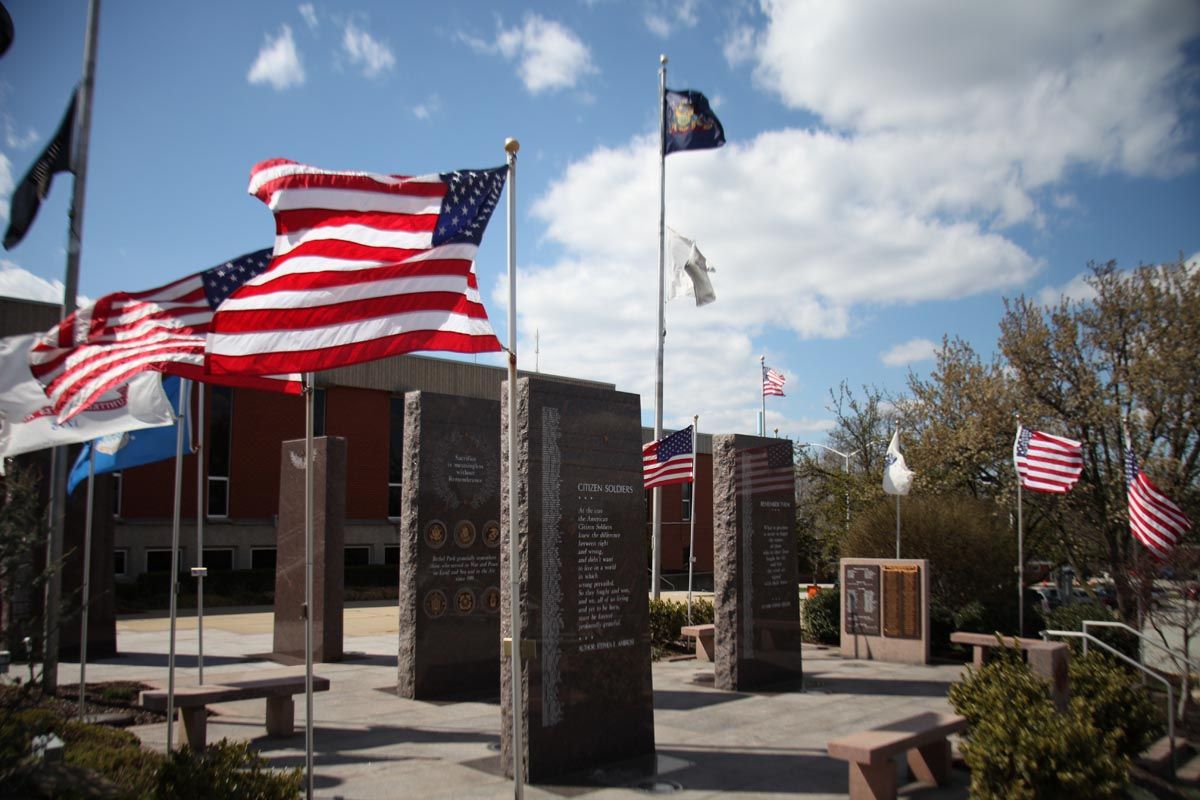 American flags flying outside a brick building on a sunny day