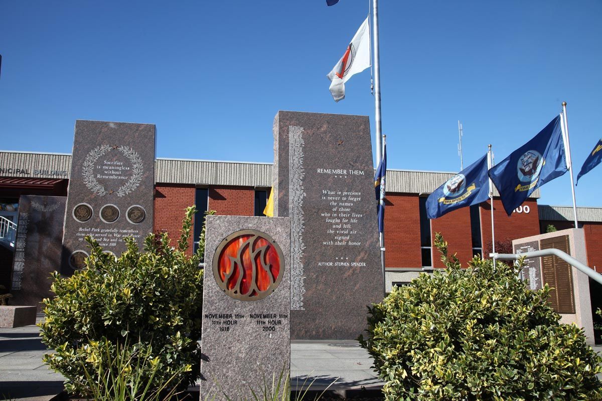Memorial stones and flags outside a building under a clear blue sky