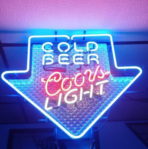 Blue neon arrow sign reading “Cold Beer” and “Cool Light” in red and white.