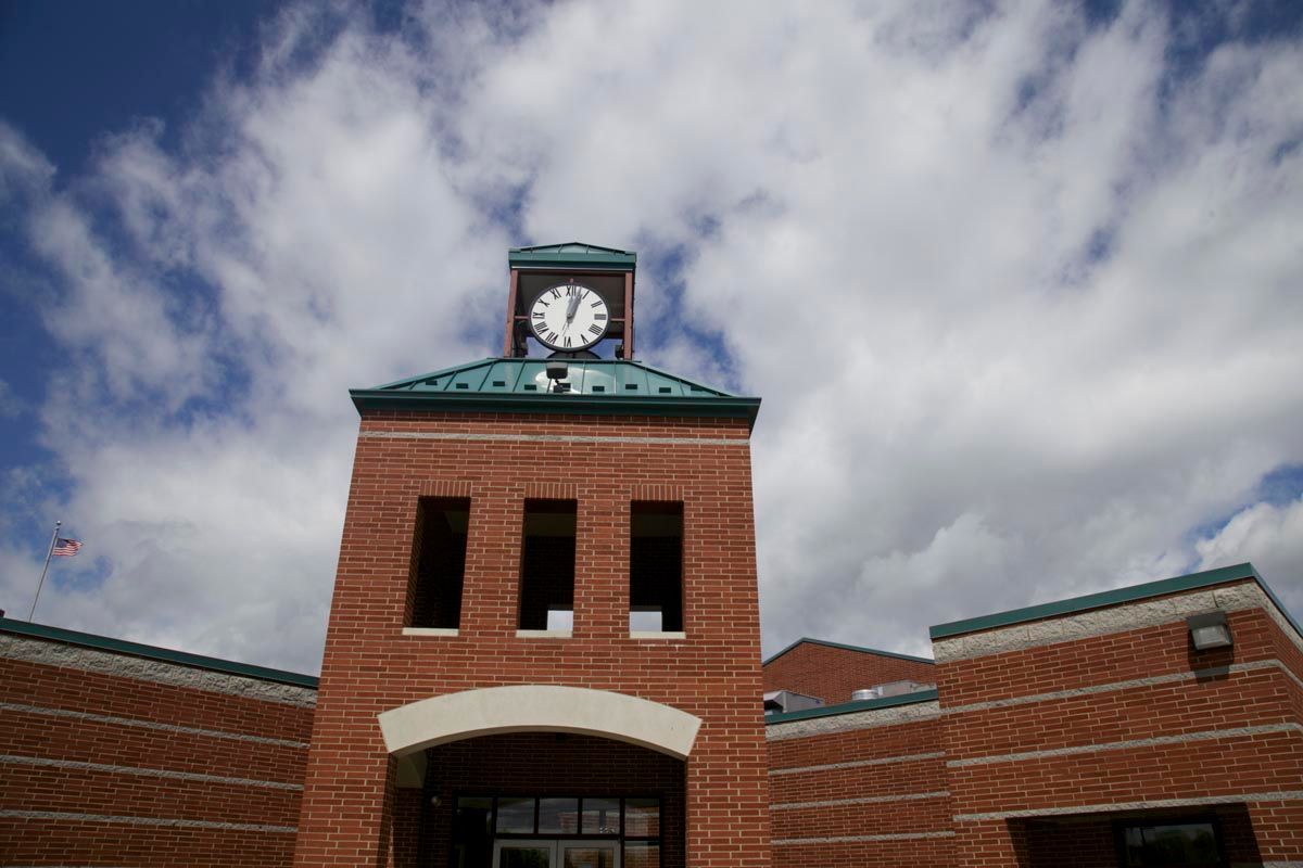 Brick clock tower on a building under a cloudy sky