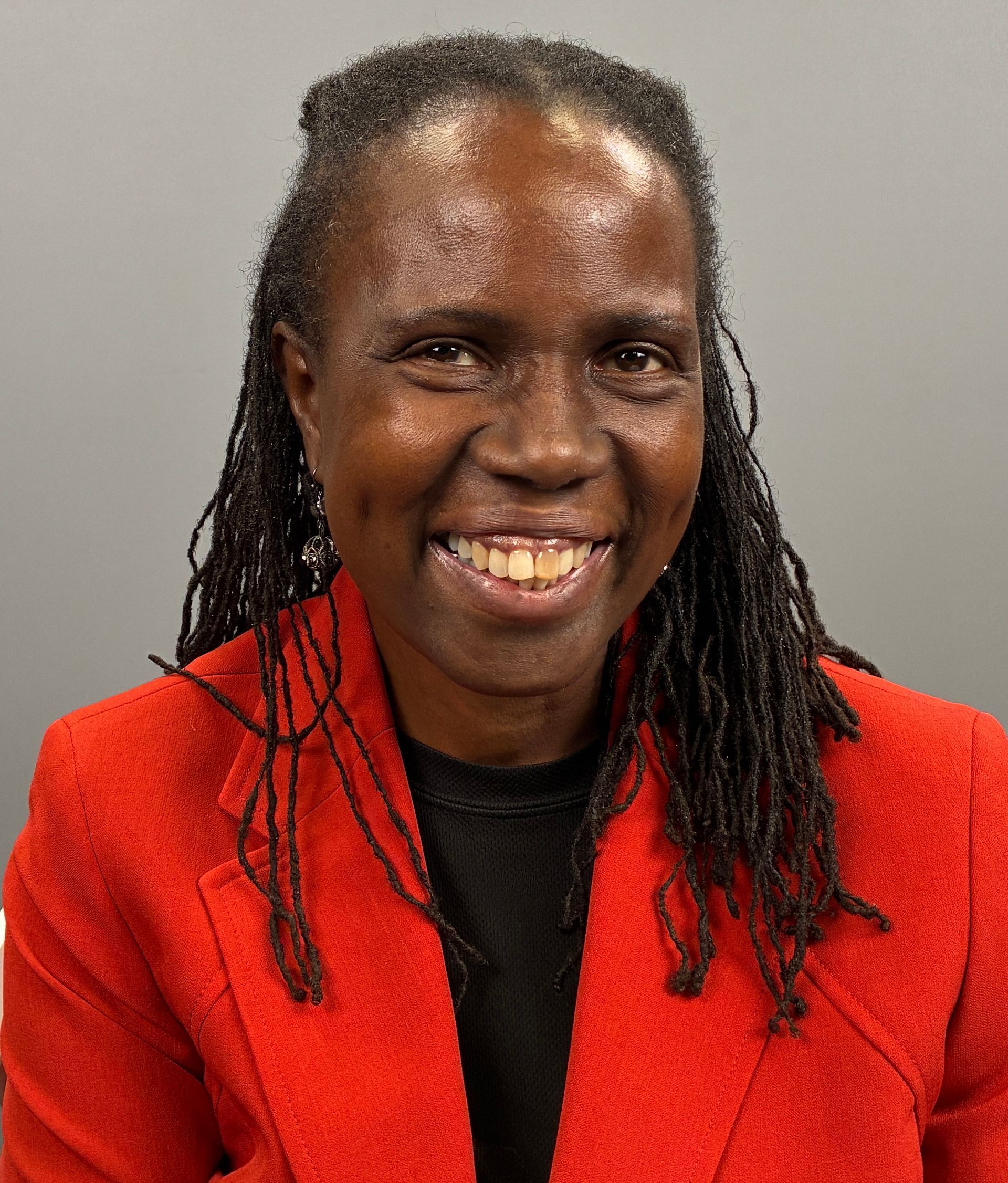 Woman smiling in a red jacket against a gray background
