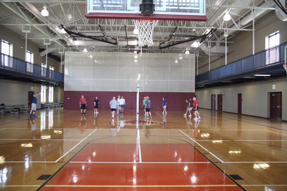 Indoor basketball gym with players lined up on the court during practice.