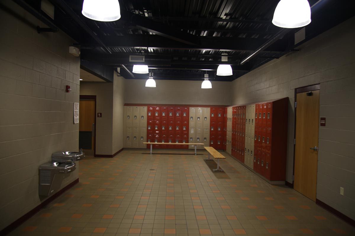 Empty school hallway with red lockers, beige walls, and overhead lights
