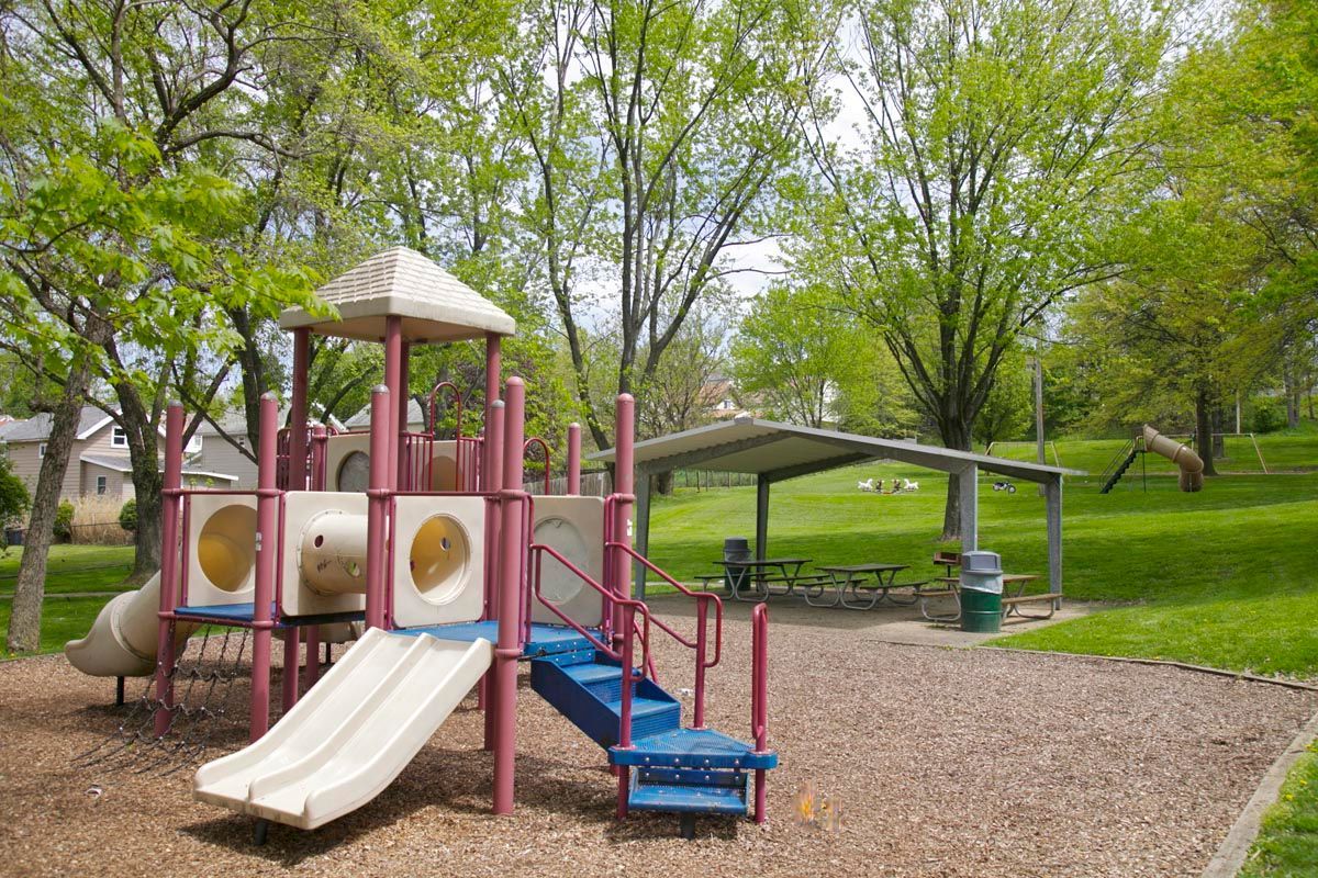 Playground with slides and climbing structures in a green park under trees