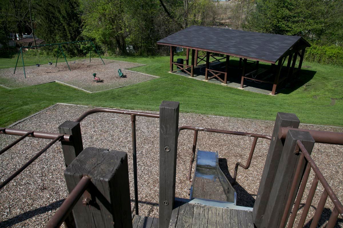 Wooden stairs overlook a grassy park with a gazebo, picnic area, and playground sandpit.