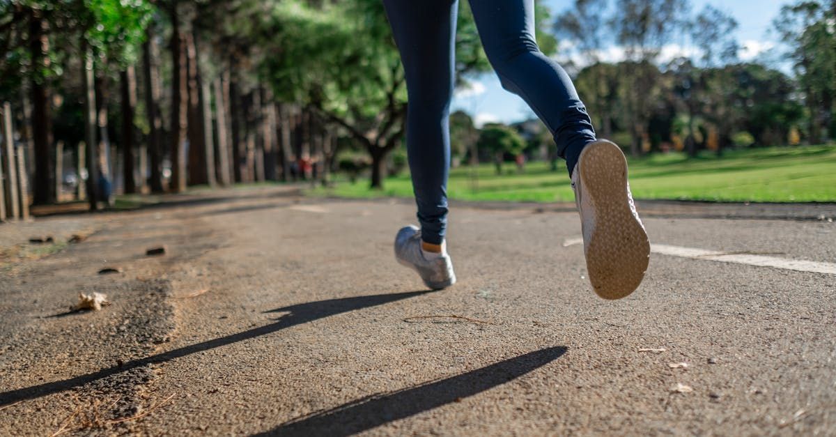 Person running on a park path, seen from behind with close-up legs and sneakers.
